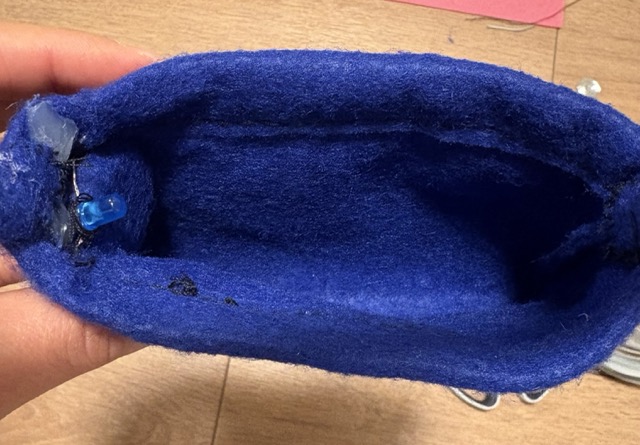 Added a battery pouch connected to two wires. The wires are hidden at the top pf the purseand make the opening more stable. The LED light is connected to the wires coming out of the pouch. 